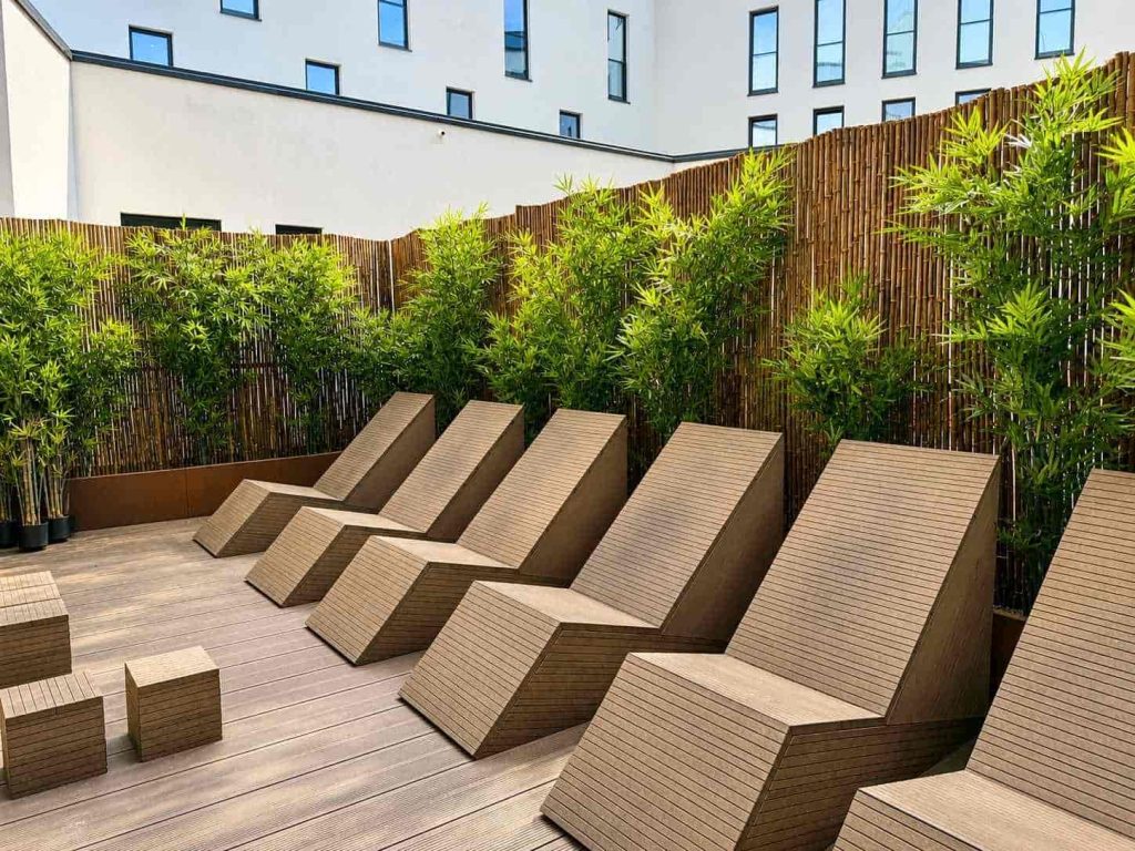 Blickdichter und pflegeleichter Balkon Sichtschutz ideal auch für gewerbliche Bereiche mit Bambusmatte, länglichen Pflanzkübeln und Kunstbambus