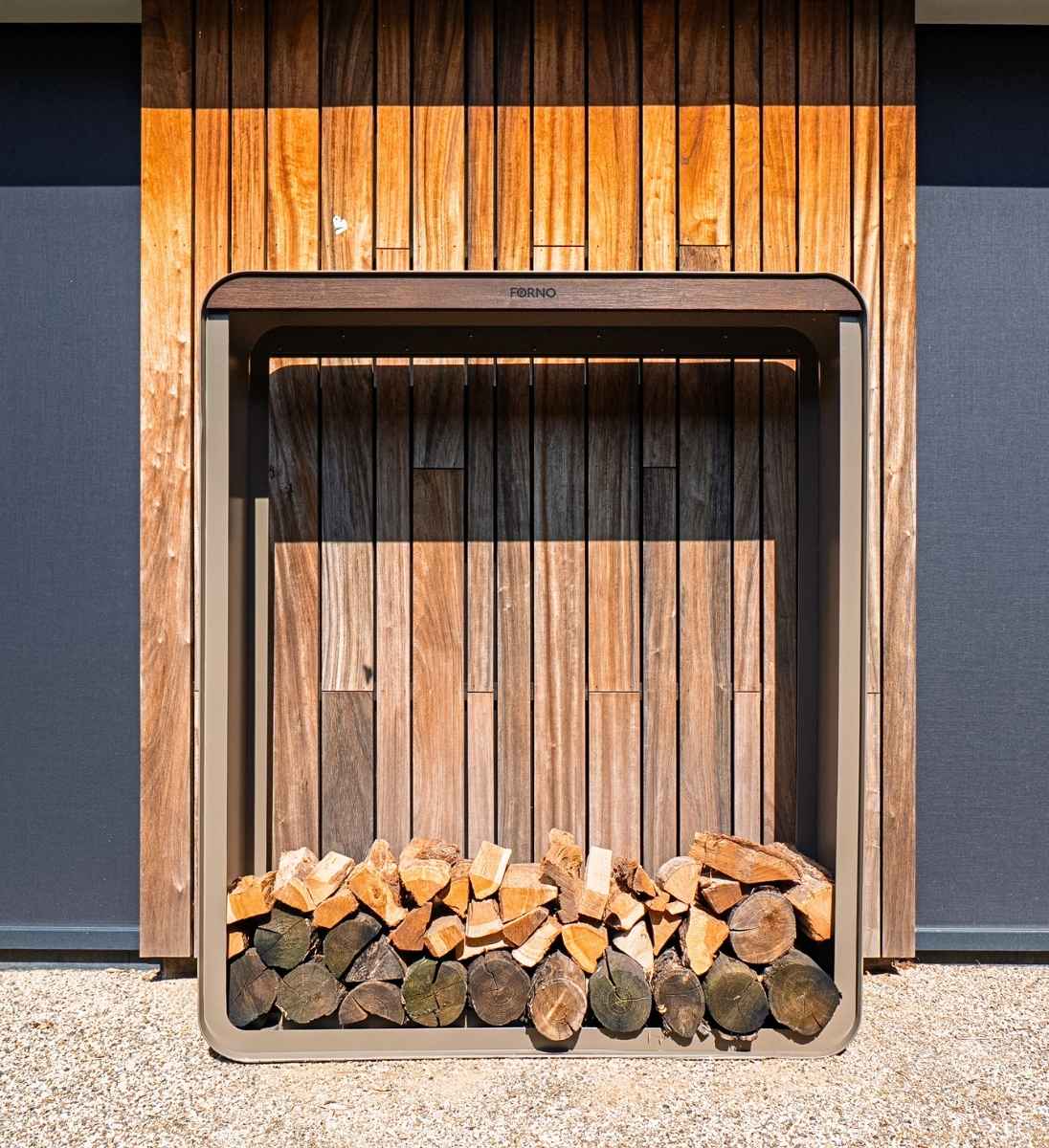 Großes Kaminholzregal SERRA aus Aluminium 150 × 40 × 180 cm mit Bambusleiste, aufgestellt an einer modernen Holzfassade