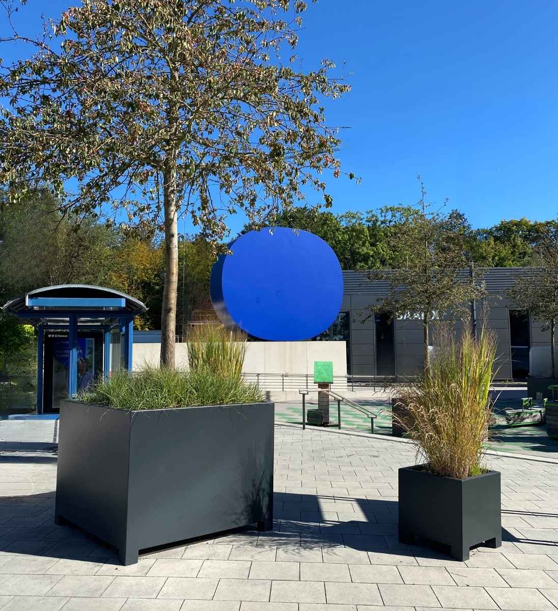 Moderner quadratischer Pflanzkübel mit Füßen aus Alu im öffentlichen Stadtpark