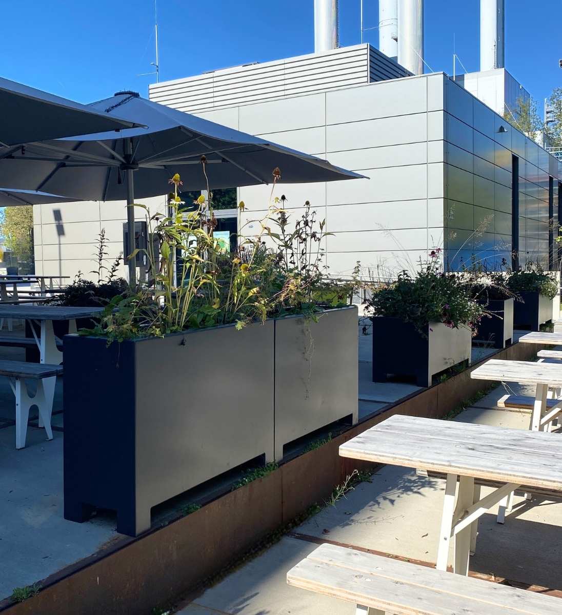 Langes rechteckiges Aluminium Pflanzgefäß mit Füßen als Raumteiler auf Terrasse mit Staudenbepflanzung