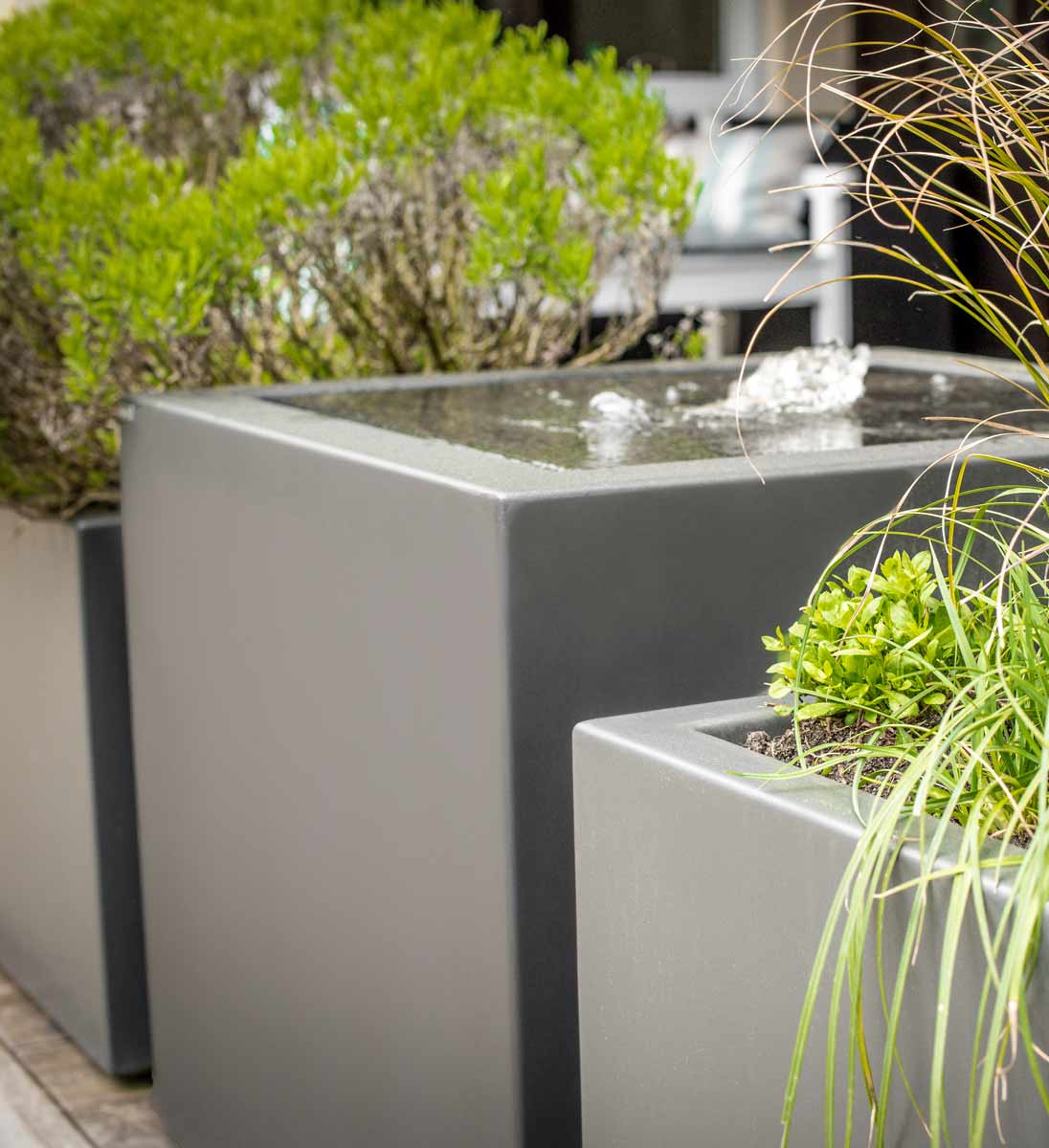 Moderner Wasserbrunnen Gartensilber Wasserkubus im zeitgemäßen Garten