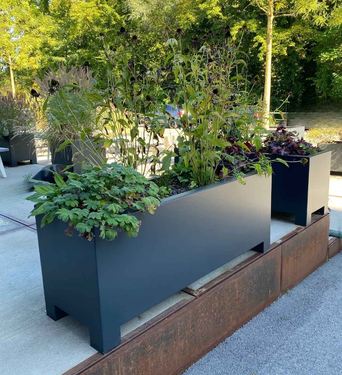 Rechteckiger Pflanzkübel aus Aluminium mit Füßen, bepflanzt mit bunten Sommerblumen auf Terrasse